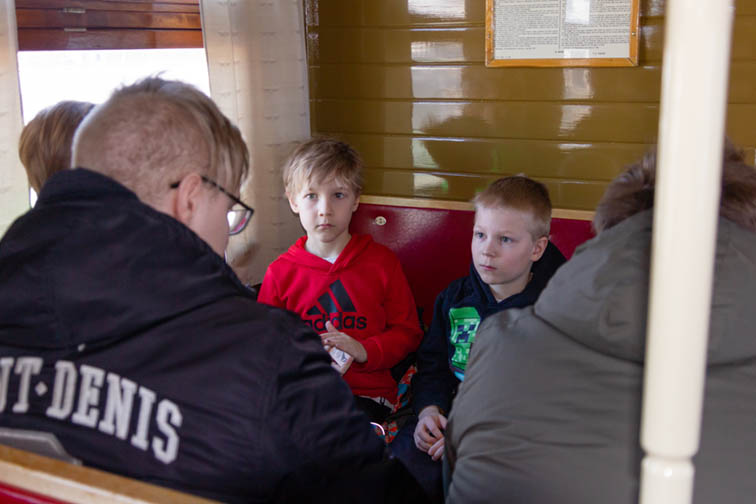 Eri-ikäisiä poikia istumassa junan vaunun penkeillä.