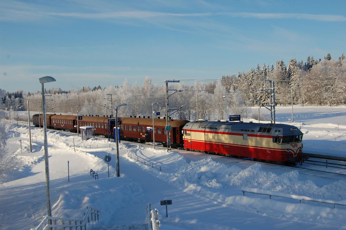 Perinnejuna Valtteri on liikenteessä lumisissa talvimaisemissa punakeltaisen dieselveturin vetämänä.